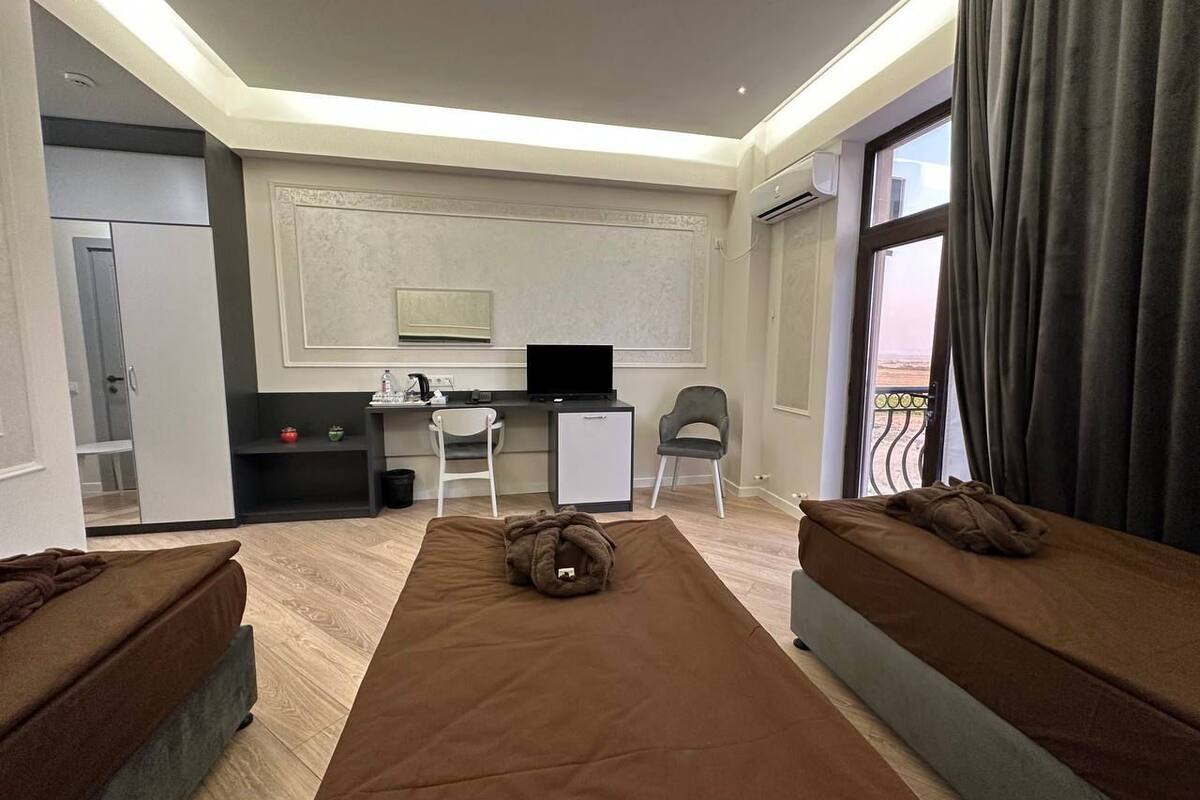 Een hotelkamer met twee bedden, een bureau, een stoel, een televisie en een balkon met uitzicht.