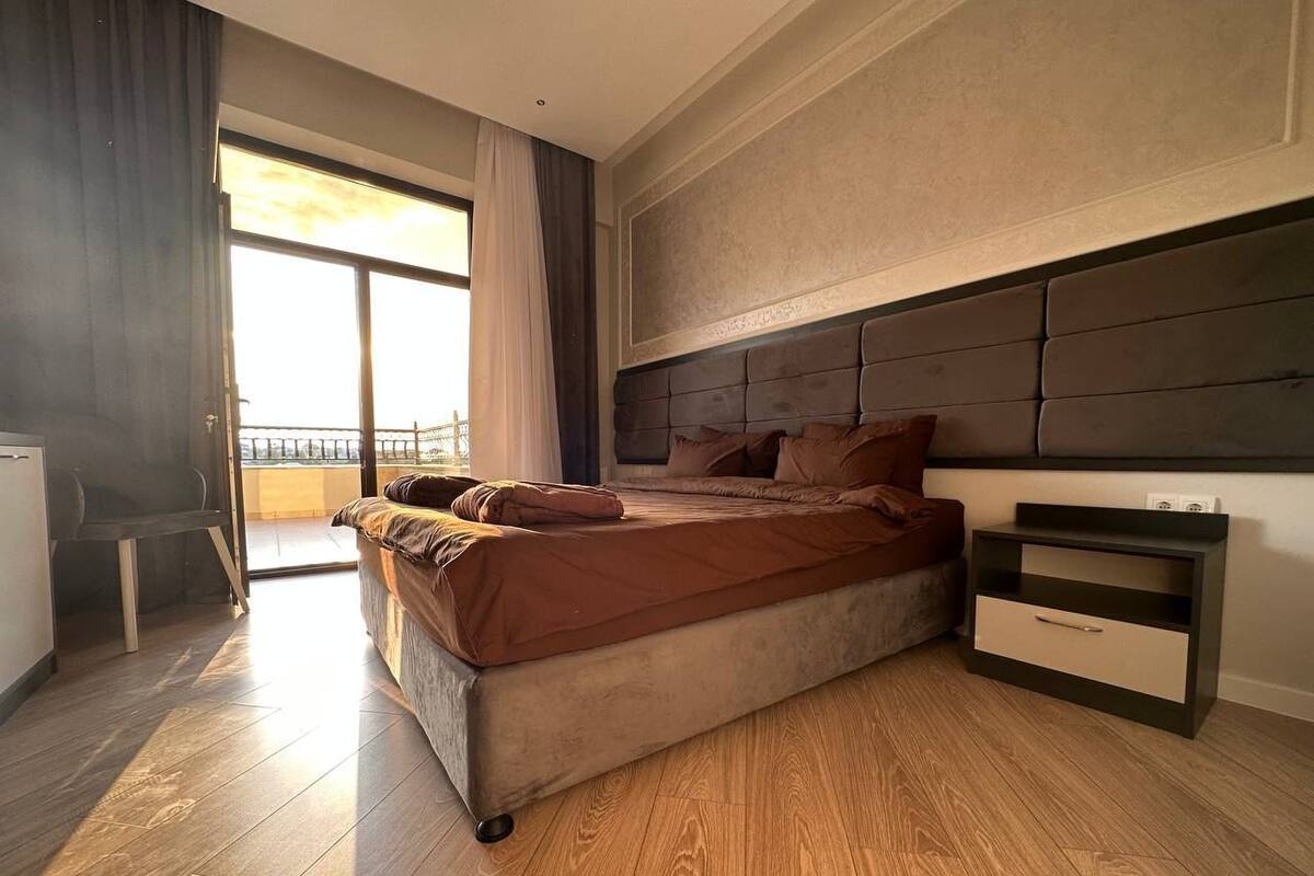Een moderne slaapkamer met een groot bed, een nachtkastje en uitzicht op de omgeving.