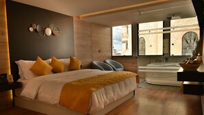 Un dormitorio moderno con una cama grande, vista a un edificio histórico y un espacio de baño separado.