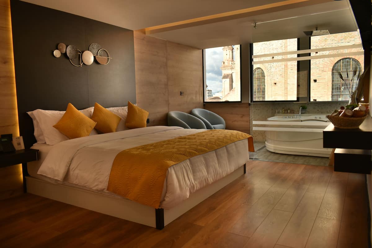 Un dormitorio moderno con una cama grande, vista a un edificio histórico y un espacio de baño separado.