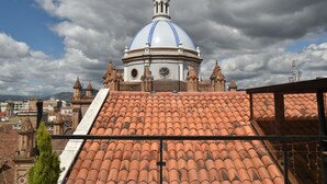 Un edificio abovedado con una torre de reloj, tejas de terracota y vistas de la ciudad circundante.