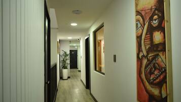 A hallway with a potted plant, a painting, and a door at the end.