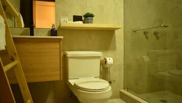 A bathroom with a toilet, a shower, and a shelf with toiletries.