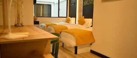 Una habitación de hotel con dos camas, un escritorio, una silla, una lámpara y una ventana.