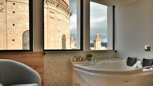 Un baño moderno con una bañera grande, vista a un edificio histórico y un revestimiento de pared de madera.
