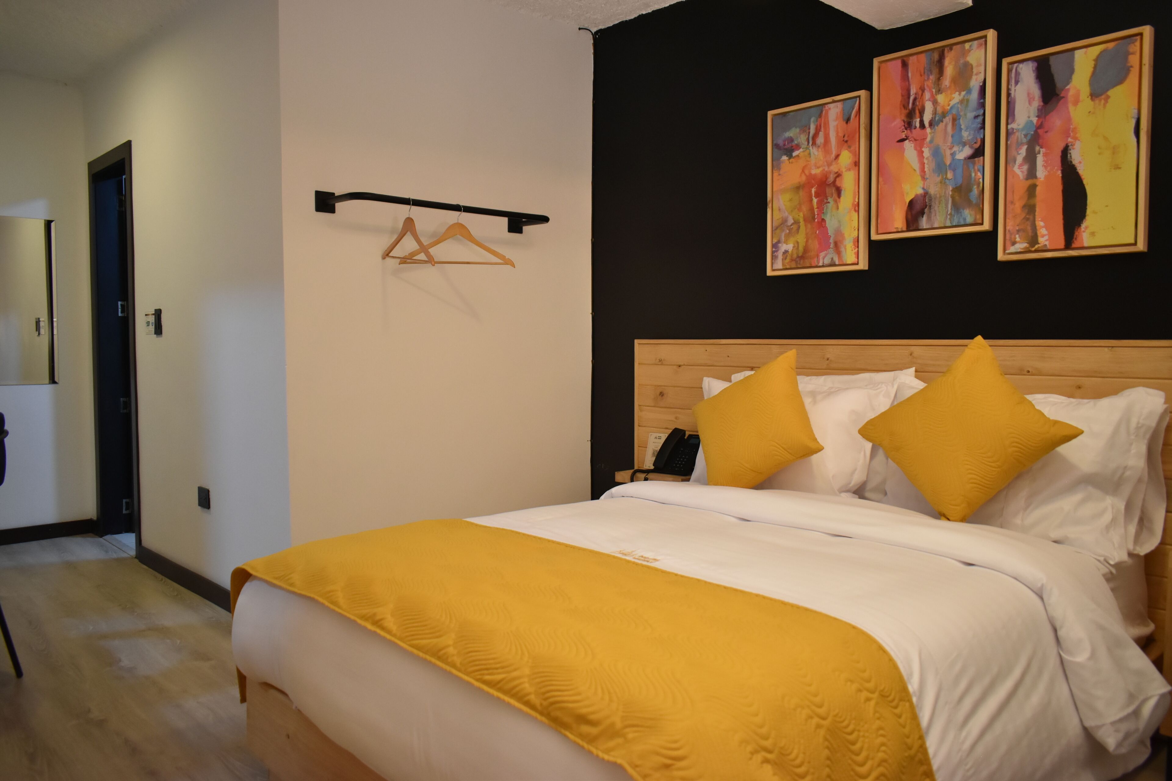 A bedroom with a bed, a wooden headboard, and two yellow pillows.