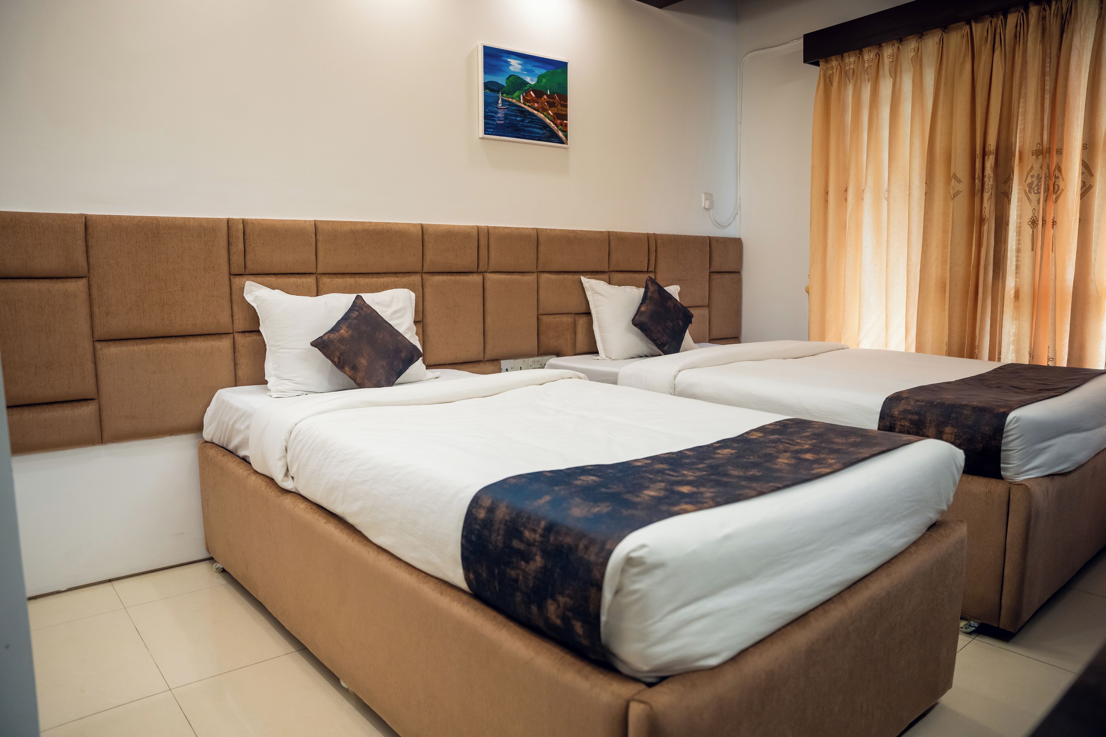A hotel room with two beds, a headboard, a painting on the wall, and a curtain.