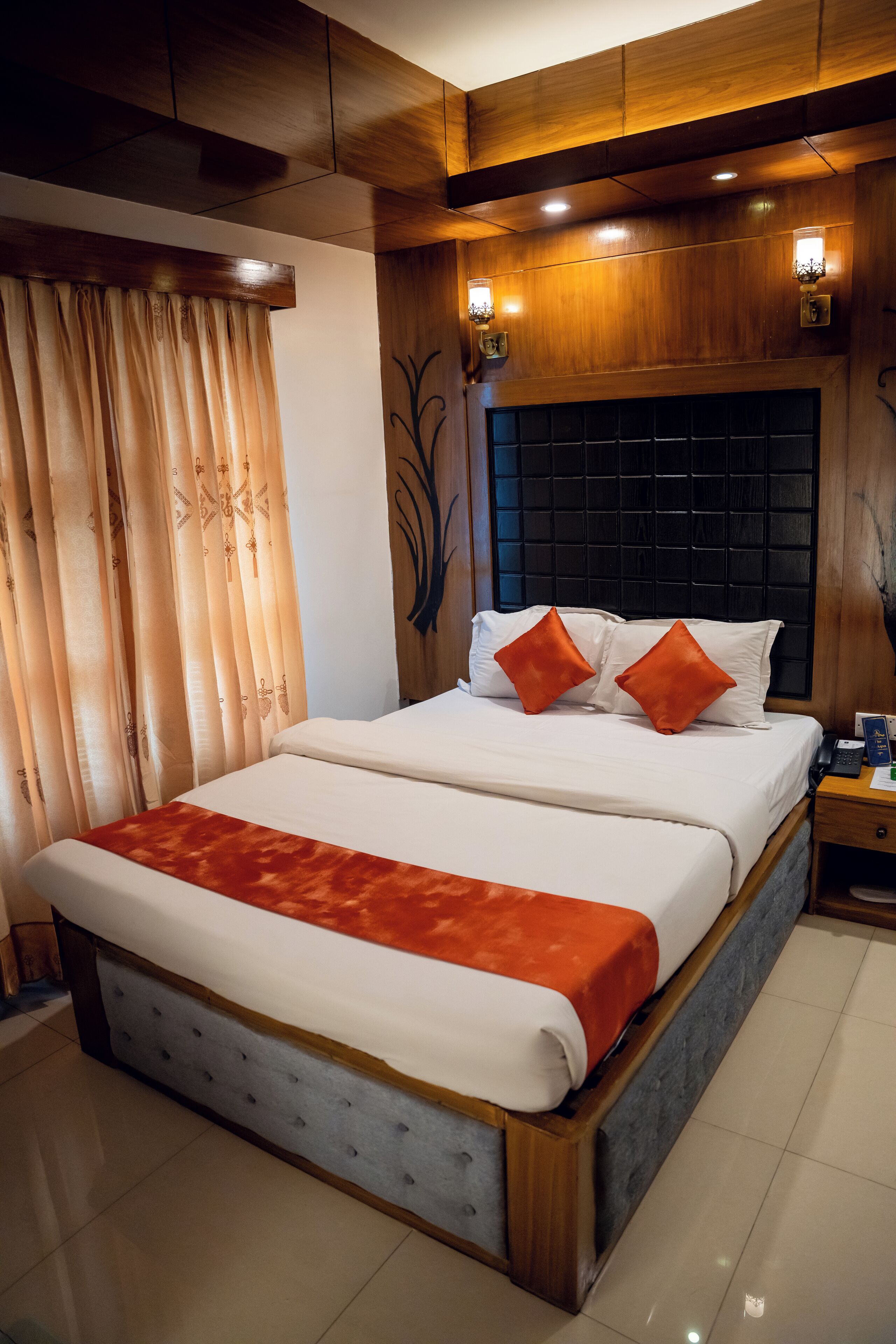 A double bed with a red throw, wooden headboard, and two bedside lamps.