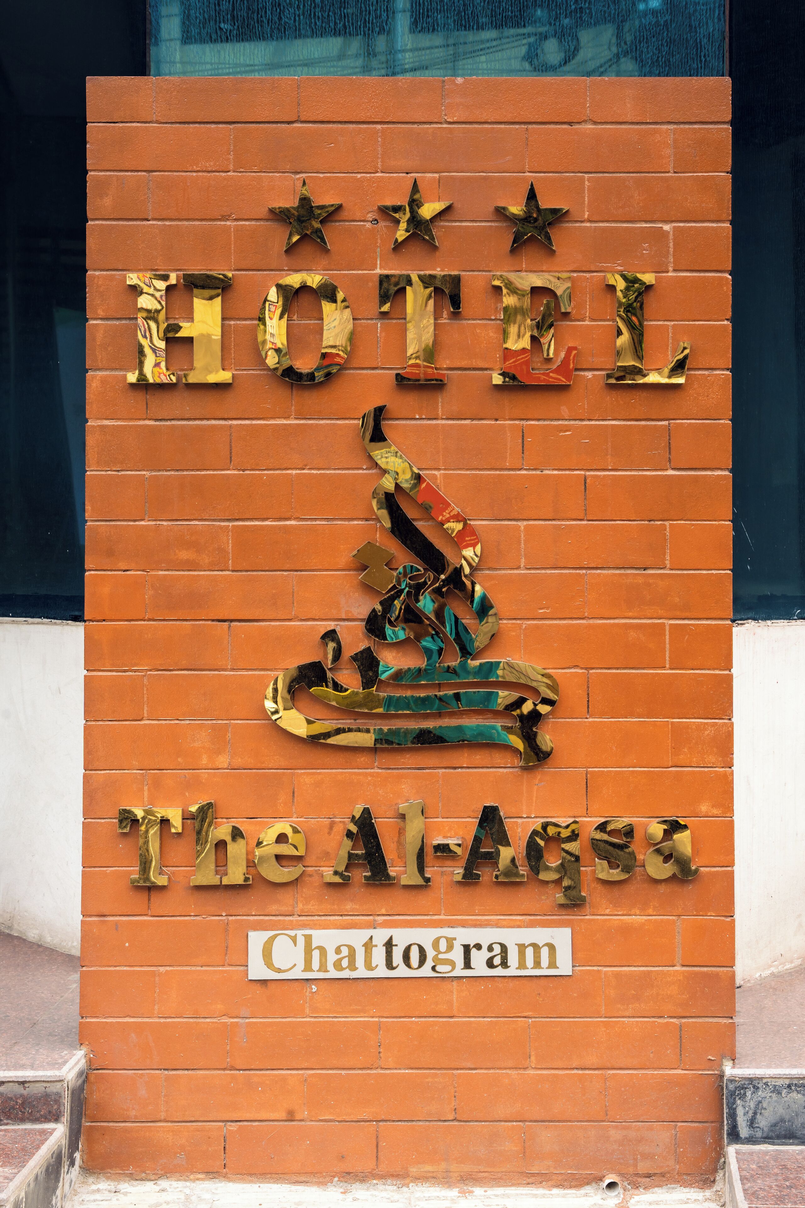 Une enseigne d’hôtel portant le nom « The Al-Aqsa » et le mot « Chattogram » en dessous.