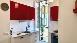 Een moderne keuken met rode kastjes, een spoelbak en een fornuis.