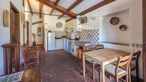 Une cuisine rustique avec des poutres apparentes, un pare-feu en carreaux et une table à manger en bois, assortie de chaises.