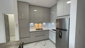 A modern kitchen with grey cabinets, a stainless steel refrigerator, and a built-in oven. - Dow Town Luxury Loft  (Monterrey)