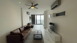A modern living room with a brown leather sofa, a coffee table, a flat-screen TV, and a ceiling fan. - Dow Town Luxury Loft  (Monterrey)