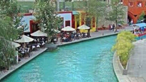 A swimming pool with a water slide, surrounded by outdoor seating areas and a red building in the background. - Dow Town Luxury Loft  (Monterrey)
