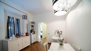 A modern kitchen with white cabinetry, a dining table, and a chandelier. - Navona Vita Suites (Rome)