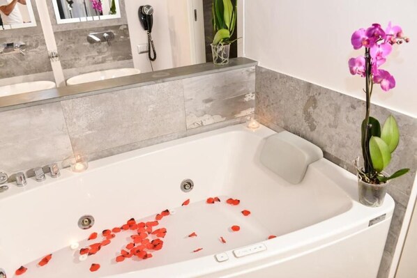 Une salle de bain avec une baignoire, deux lavabos, un sèche-cheveux et une orchidée en pot.