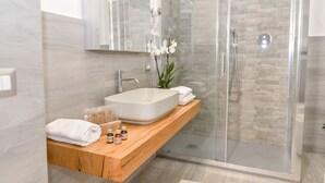 A modern bathroom with a large white sink, a glass shower enclosure, and a wooden vanity. - Navona Vita Suites (Rome)