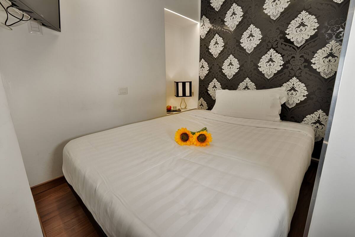 A neatly made bed with a white bedspread and two sunflowers on it.