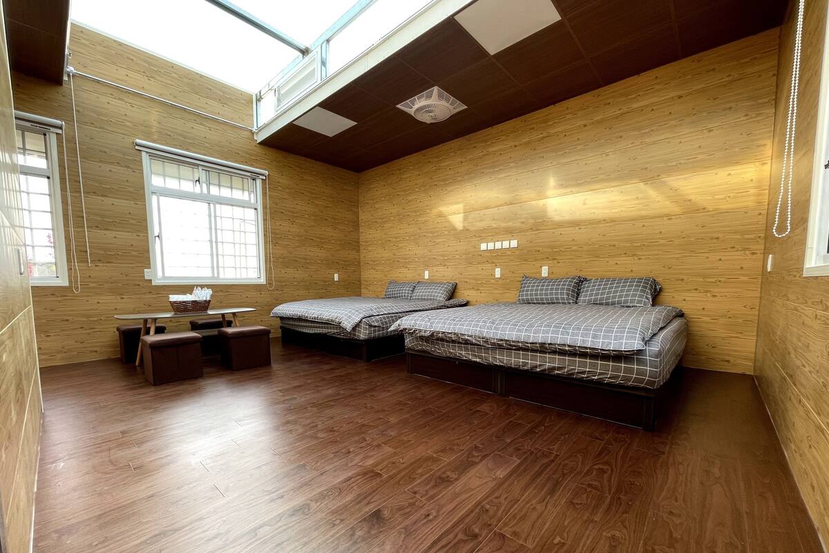 A room with two beds, a small table, and a bench.