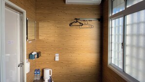 Casa de banho com painéis de madeira, uma janela, porta-toalhas, pia com artigos de higiene e unidade de ar condicionado.