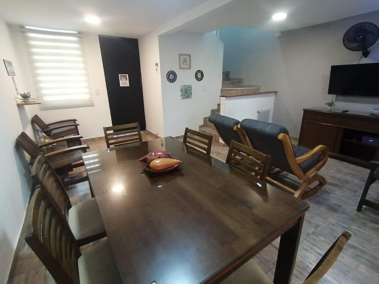 A dining area with a wooden table and chairs, a small decorative bowl, and a staircase leading to an upper level.