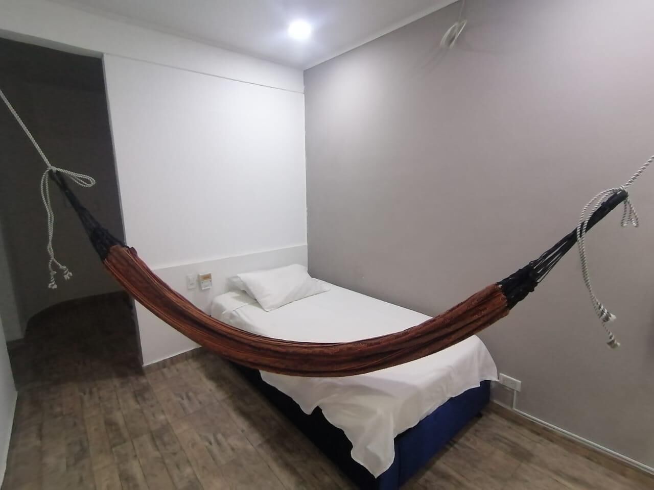 A room with a bed, a hammock, and a wooden floor.