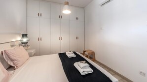 Une chambre à coucher comprenant un lit, une armoire, une table de chevet, une lampe et un appareil de climatisation.