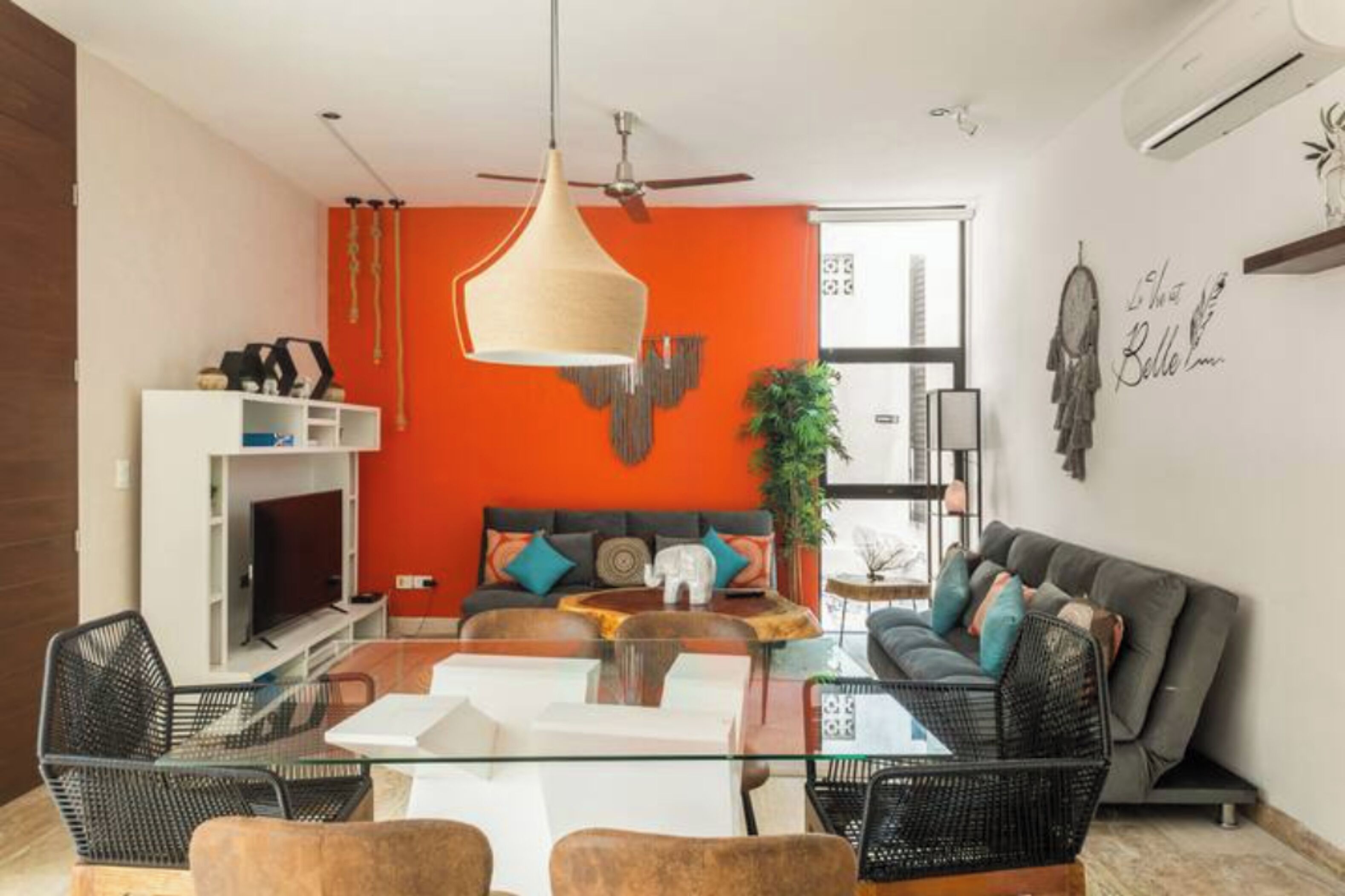 Una sala moderna con una mesa de centro de vidrio, un sofá y un comedor con sillas.