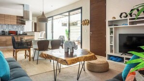 Uma sala de estar moderna com uma mesa de jantar de madeira, um sofá e uma televisão.