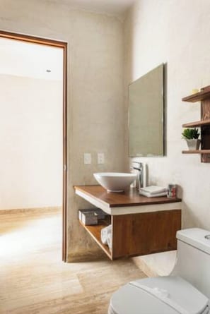 A modern bathroom with a wooden vanity, a white sink, a mirror, and a toilet. - Magnificent Apartment Pool Gym (Tulum)