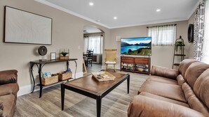 Un salon avec un canapé en cuir marron, une table basse en bois et un téléviseur fixé au mur.