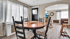 Un coin repas avec une table ronde en bois, des chaises noires et des coussins à motifs.