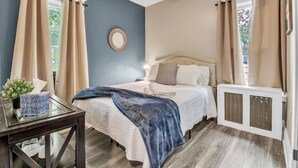 Une chambre à coucher avec un lit, une table de chevet et une fenêtre avec des rideaux.