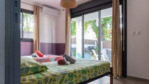 A room with a bed, a window, and a view of the outside. - Appartement Neuf et son Jardin Pieds Dans le Sable (Saint Paul)