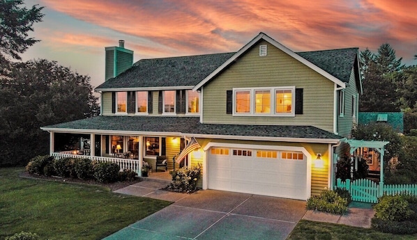 A two-story house with a covered porch, a garage, and a well-maintained lawn.