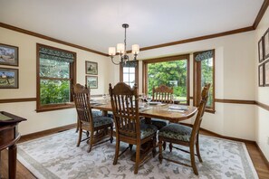 A dining room with a wooden table, six chairs, and a chandelier.