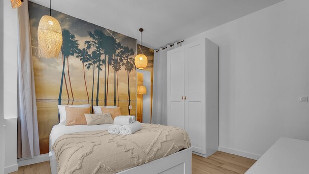 Une chambre à coucher comprenant un lit, une armoire, un luminaire suspendu et une fresque murale.