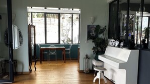 Ein geräumiger Raum mit Holzboden, einem Klavier, einem großen Spiegel und Blick durch ein Fenster.