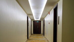Un pasillo de hotel con alfombra estampada, puertas a ambos lados y una lámpara en el techo.