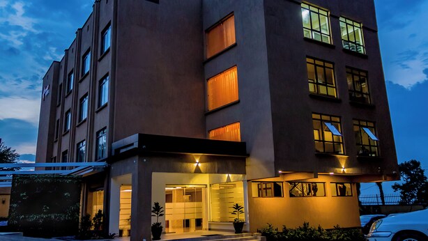 Un hotel de varios pisos con un diseño moderno, que cuenta con una entrada a nivel de calle con fachada de vidrio y un área exterior cubierta.