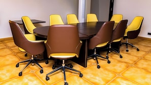 Un salón de conferencias con una mesa redonda y sillas, un equipo de aire acondicionado grande y un suelo de baldosas.