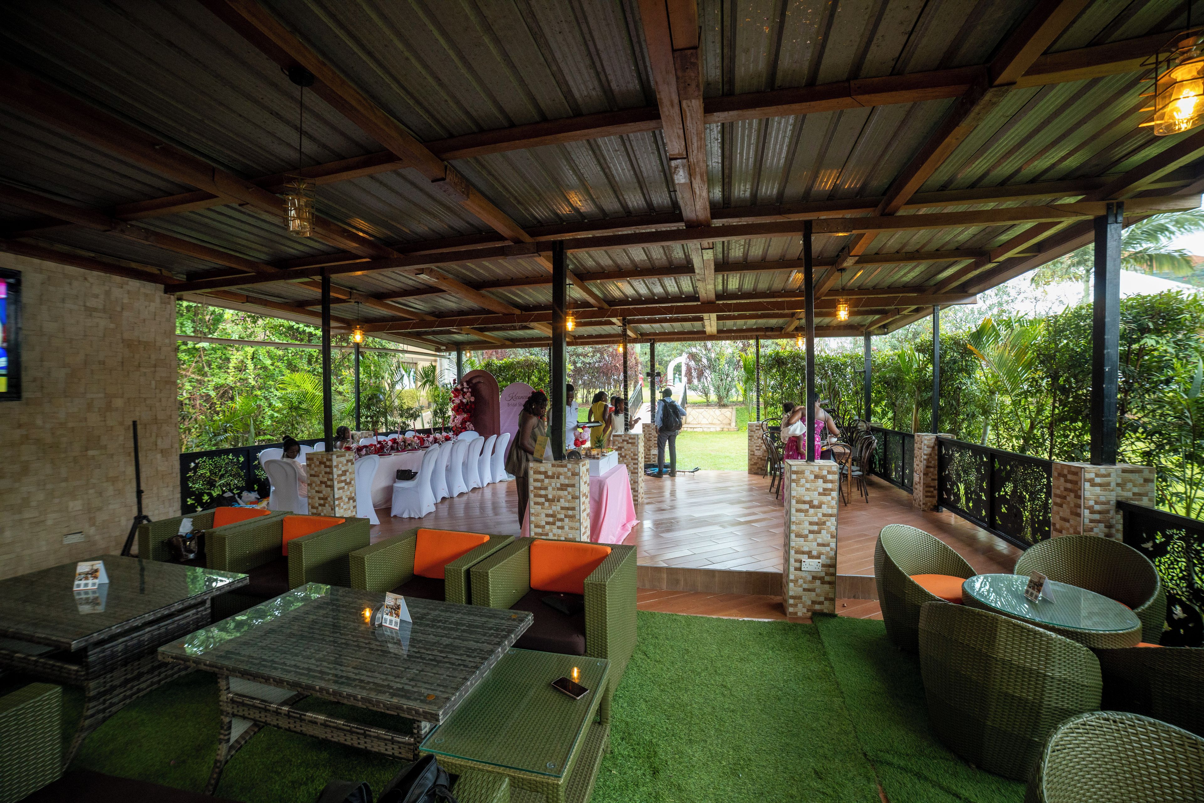 An outdoor patio area with wicker furniture, a brick wall, and a view of greenery.