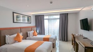 Una habitación de hotel con dos camas, un escritorio y una televisión.