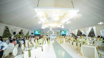 Un espacio para eventos con carpas, mesas redondas, sillas y un escenario.