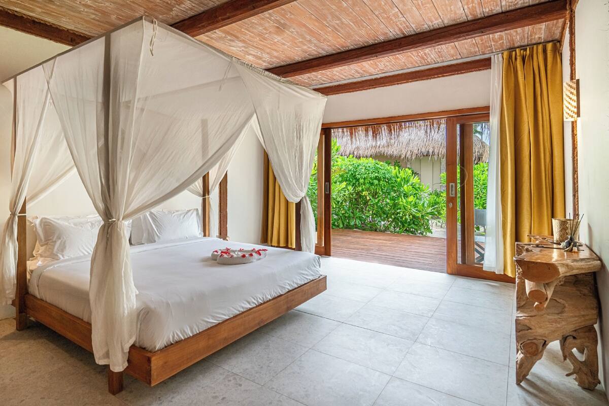 Un dormitorio amplio con una cama grande, un dosel y vistas a exuberante vegetación.