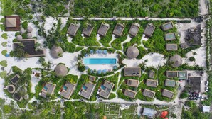 An aerial view of a resort with multiple bungalow-style accommodations, a central swimming pool, and lush greenery. - Sensations Eco-Chic Hotel (Pwani Mchangani)