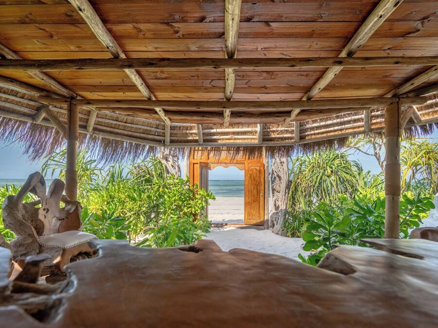 Une structure en bois surmontée d’un toit de chaume, qui mène à la plage.