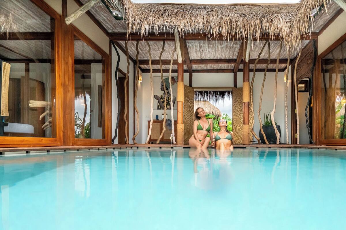 Una piscina interior con paredes de madera y techo de paja.