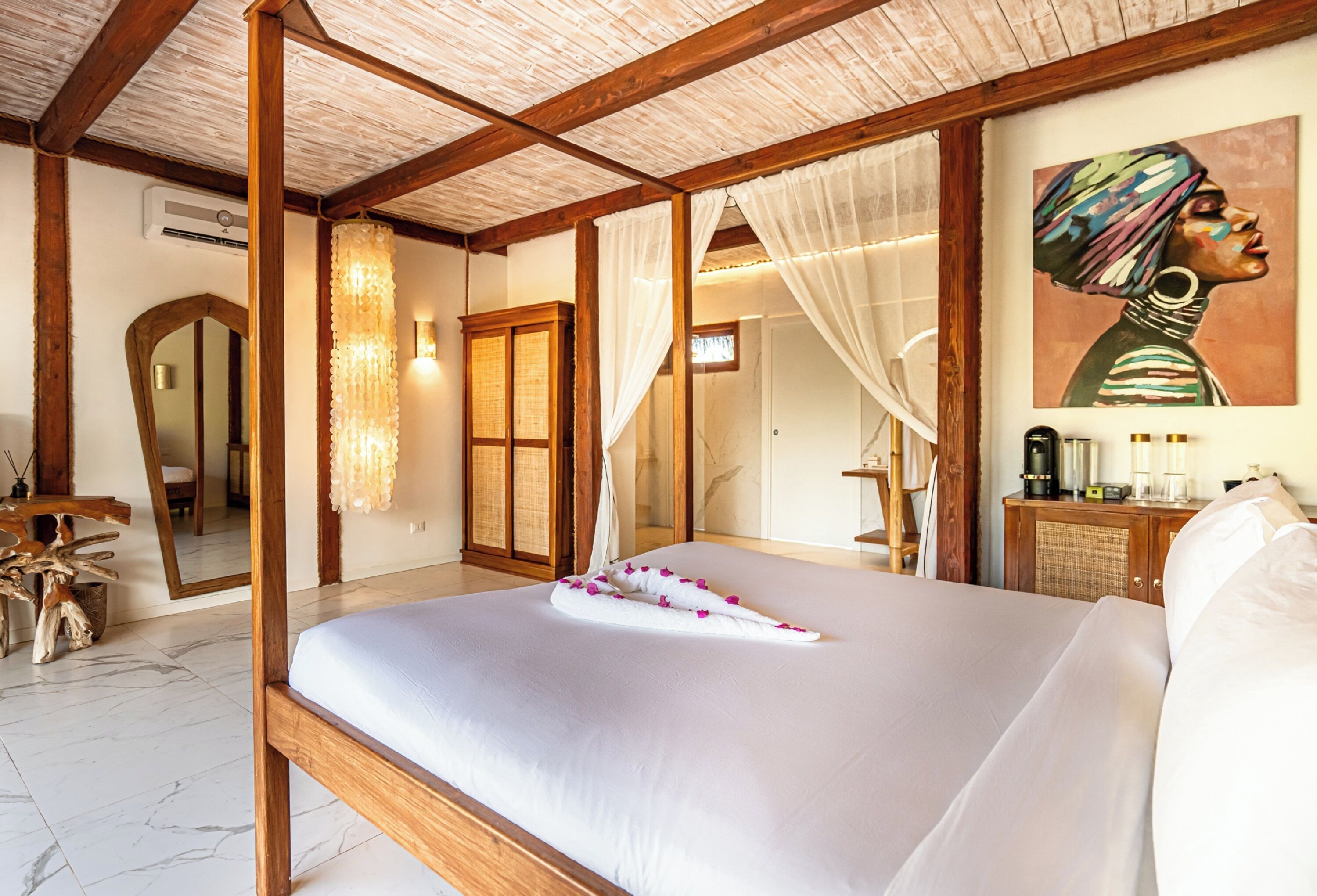 A bedroom with a large bed, wooden beams, a mirror, a painting, and a bedside table with a lamp.