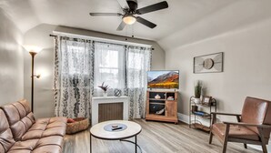 A living room with a sofa, armchair, round coffee table, fireplace, and a television. - Chic Two Bedroom near Buffalo (Buffalo)
